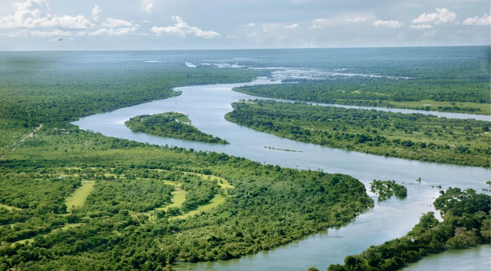Aerial view of the Zambezi River winding through a lush green floodplain with tree-covered islands