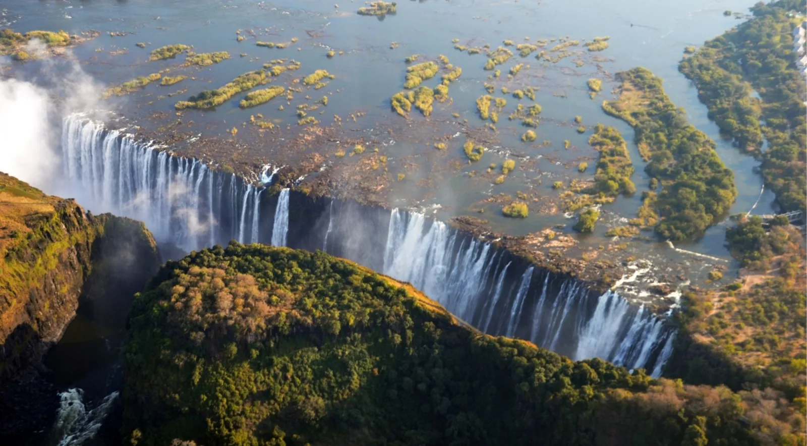Aerial photograph of Victoria Falls showing the full width of the falls cascading into the gorge with the upper Zambezi and islands visible above